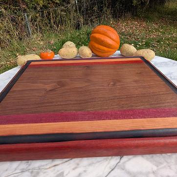 Multi-species board — walnut and cherry framed in purpleheart and bloodwood, juice groove inside the border.