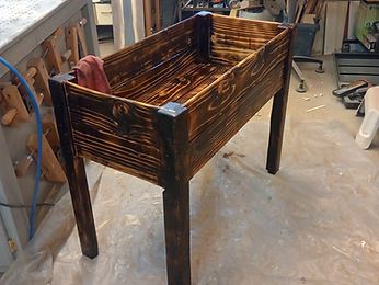 A charred timber box assembly oiled and drying on plastic sheeting in the workshop