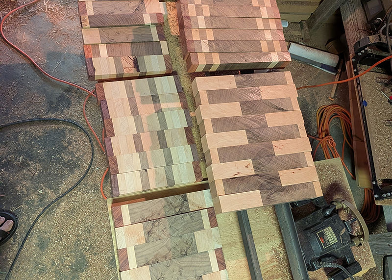 Laminated board sections laid out on the workbench mid glue-up, sawdust across the bench