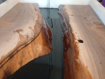 A natural crack running down a board, filled with dark resin inside a white casting frame