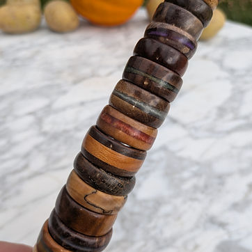 Twelve on the mandrel — pale maple at the top, near-black walnut at the base.