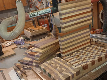 Checkerboard blocks and laminated strips being arranged for a second glue-up on the bench
