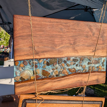 Live edge river board with creek stone set through the turquoise pour, hung by twine at the market.