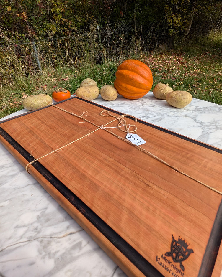 A cherry serving board with the McKnight Masterworks mark engraved in the corner