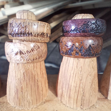 Mountain ranges burned around the band — purpleheart, walnut, and a pair with lines run right round.