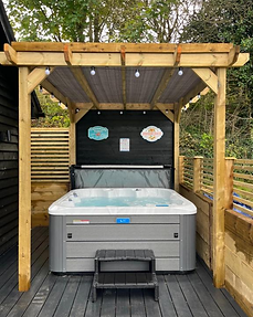 Private hot tub filled with water beneath the wooden pergola at Lydden Bell Lodge, Kent