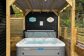 Private hot tub on the outdoor decking under a wooden pergola