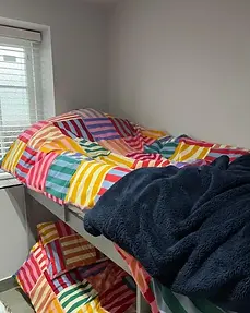 Bunk bed with multicoloured striped bedding in a bedroom at Lydden Bell Lodge