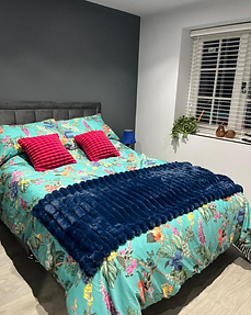 Double bedroom with bright floral duvet cover and deep navy throw at Lydden Bell Lodge