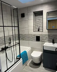 Modern bathroom at Lydden Bell Lodge with tiled bath, black framed shower screen and vanity unit