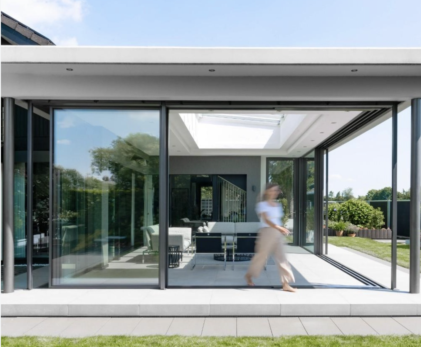 Sliding doors open across a white-tiled patio with the garden beyond