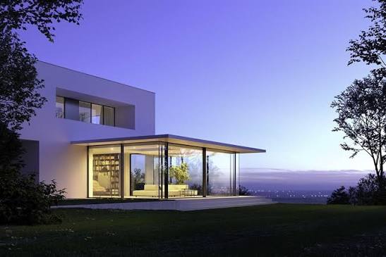 A glass room lit at twilight