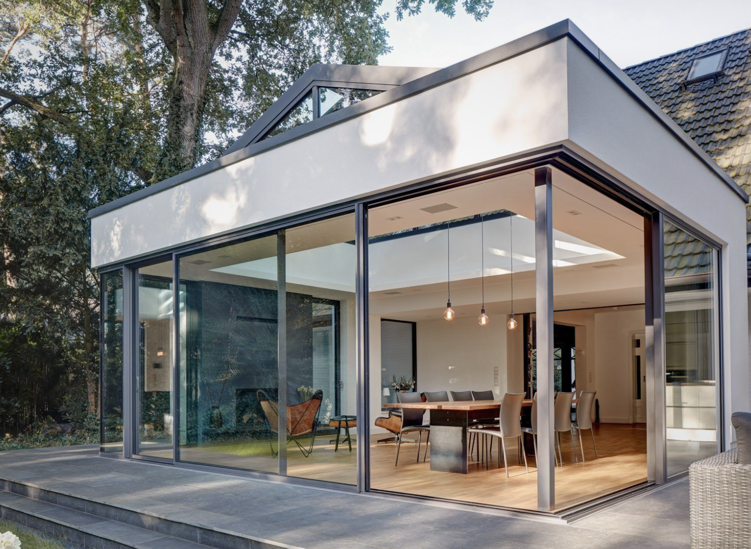 A corner sliding door system opening a dining space onto a stone terrace