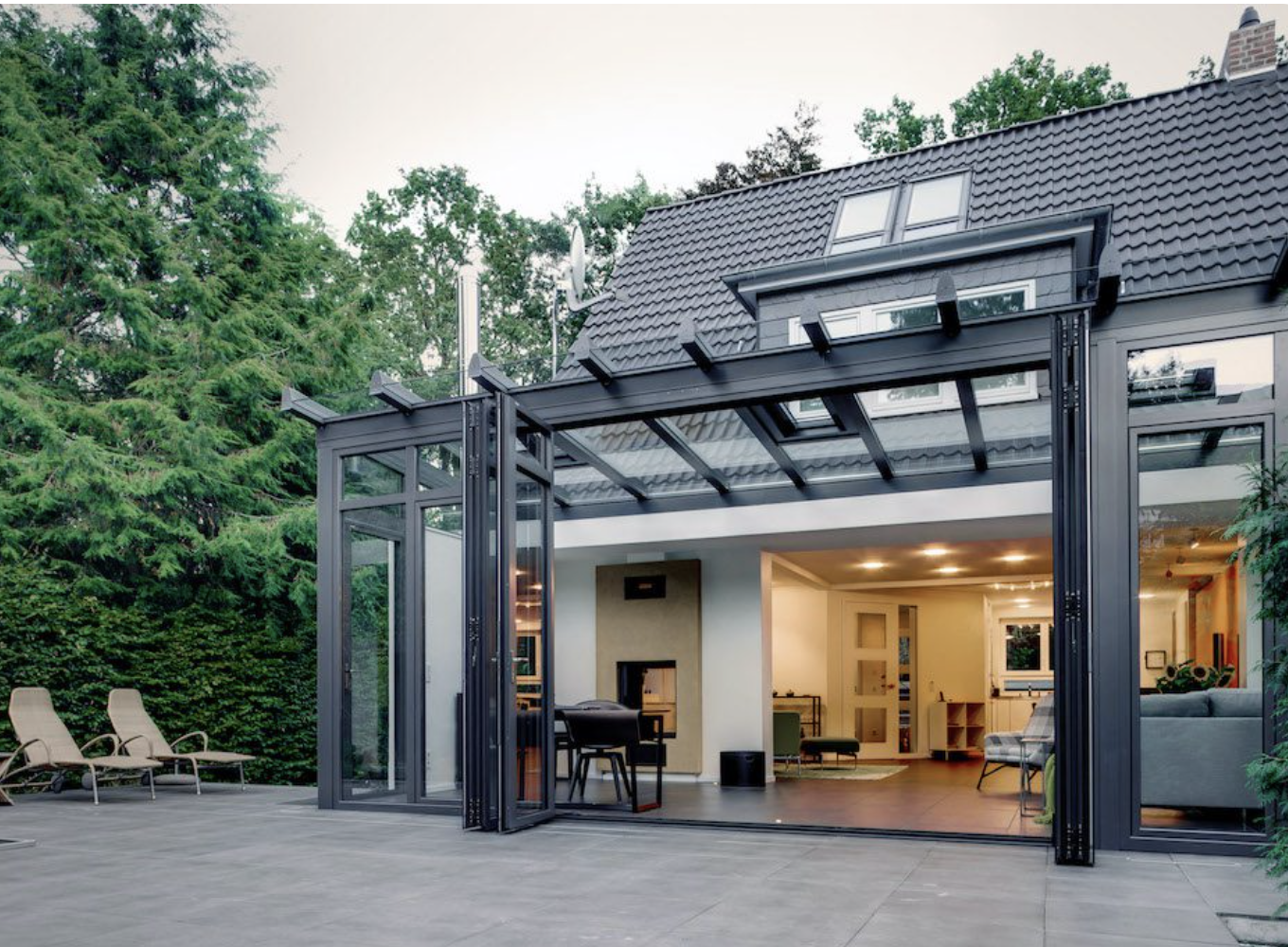 Bi-folding doors folded open from a tiled patio into a glazed living space