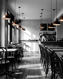 Empty café interior in black and white with bentwood chairs, wooden tables and hanging pendant lights