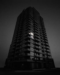 Modern residential tower at dusk with cantilevered balconies and one lit window
