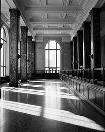 Historic banking hall with marble columns and shafts of daylight across an empty stone floor