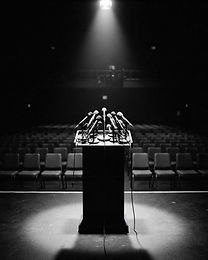 Empty podium with microphones under a single spotlight in a dark auditorium