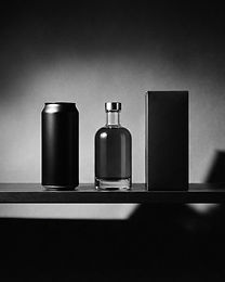 Studio still life of unbranded bottles, cans and a box on a shelf in hard side light