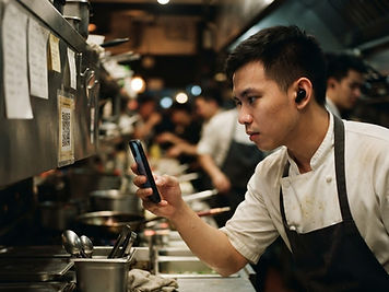 A kitchen staff member with a single earbud scanning the QR code at their station before service
