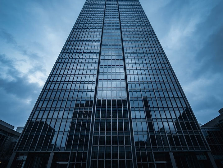 Façade d'une tour de bureaux en verre au centre-ville de Montréal, reflétant un ciel froid.