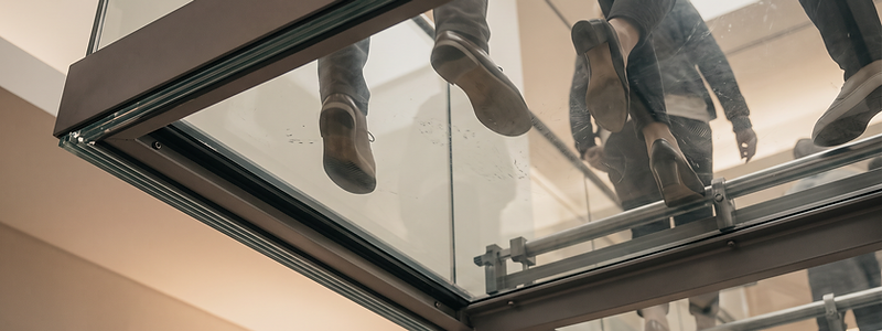 Walk-on structural glass floor viewed from below, with people walking across the panels
