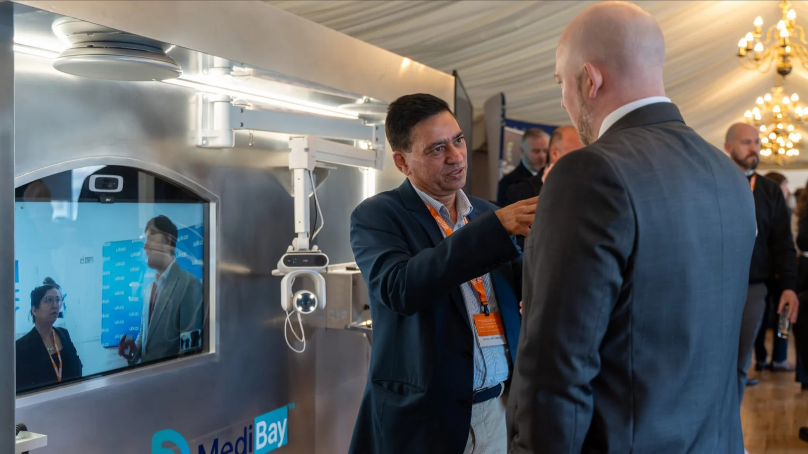 Attendees in conversation beside the MediBay TechWall at the Houses of Parliament event.
