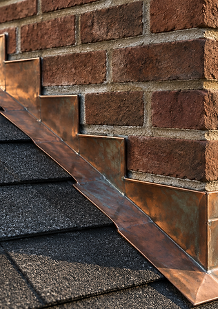 Close-up of stepped metal flashing where a roof meets a brick chimney on a residential home