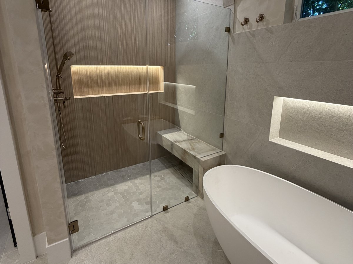 Finished bathroom with a tiled walk-in shower behind a glass panel and a freestanding tub, completed by Home Pro Green Remodeling