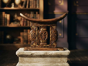 A carved ceremonial Ashanti stool in a book-lined study, representing traditional leadership and educational excellence
