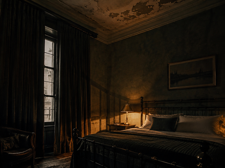 A dimly lit historic guest room with a single table lamp