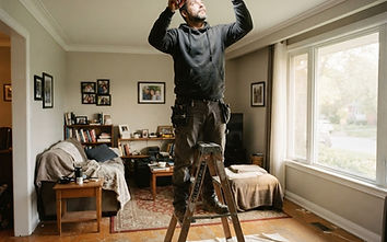 Electrician on a step ladder installing a recessed ceiling light in a Surrey living room