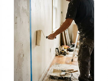 A painting contractor rolling warm off-white paint across an interior residential wall