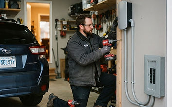 Electrician installing a Level 2 EV charger on a garage wall in an Edmonton home