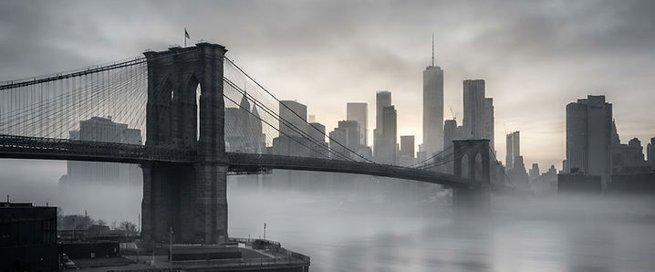 Brooklyn Bridge and the lower Manhattan waterfront at dawn in fog