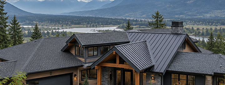 Panoramic view of a charcoal metal and shingle roof on a modern Langley home, mountains behind under an overcast sky