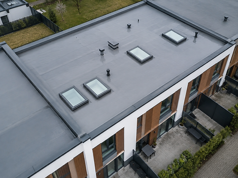 Aerial view of a low-slope townhouse roof with grey membrane and skylights