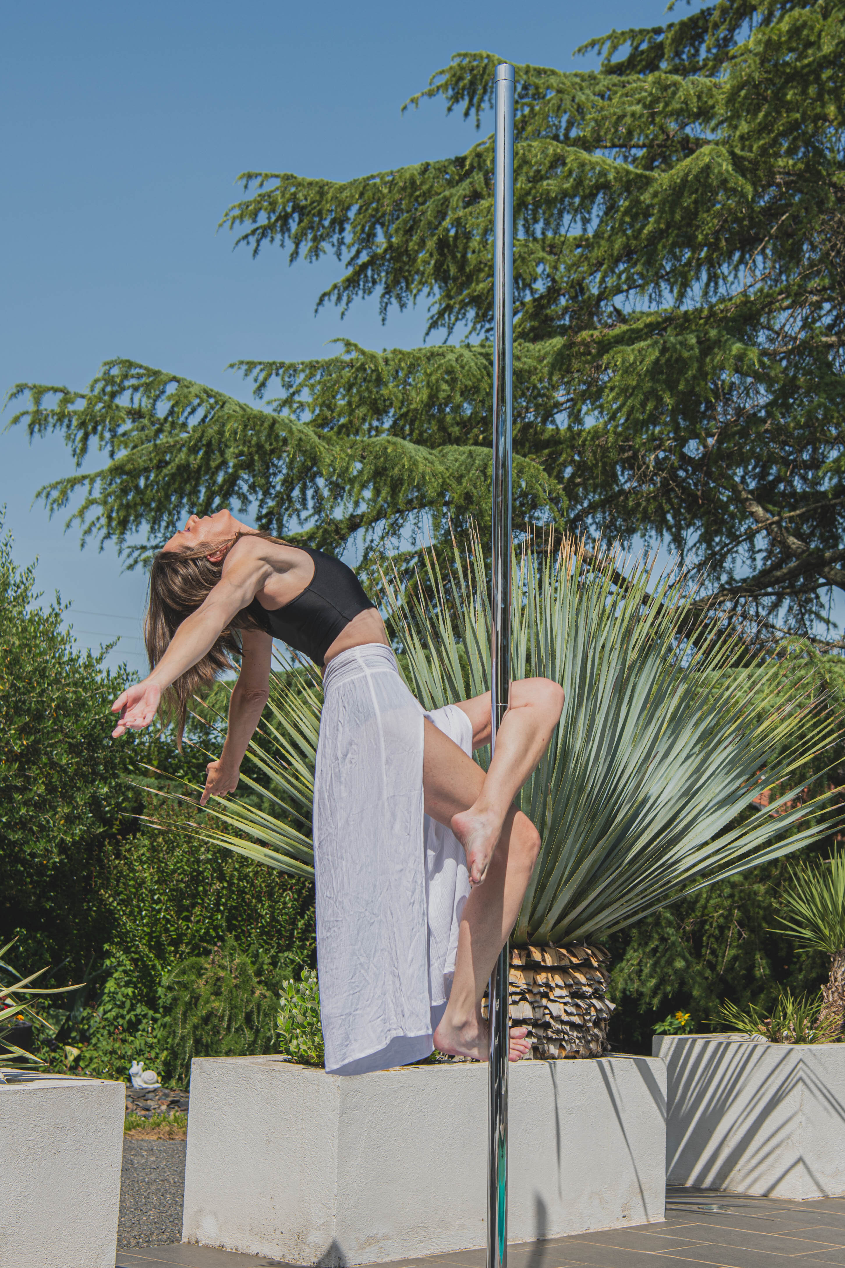 Danseuse sur une barre de pole dance dans le jardin du centre équestre