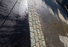 Freshly paved black asphalt driveway edged in cobblestone