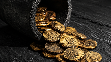 Worn gold coins spilling from a crucible onto dark slate