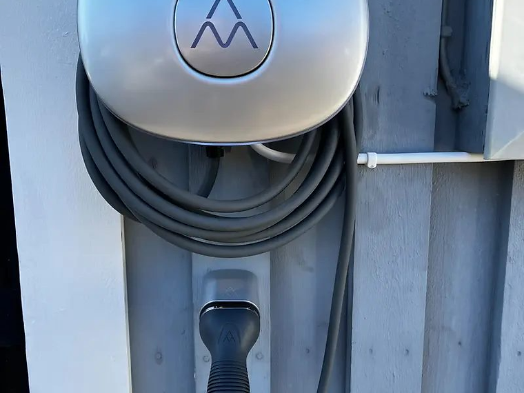 Charge Amps Halo med laddkabel på träfasad