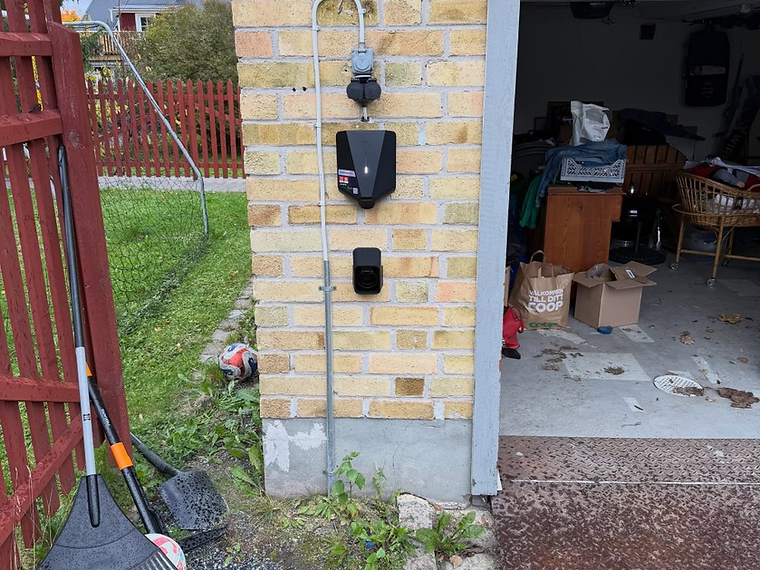 Laddbox på tegelfasad intill garageport