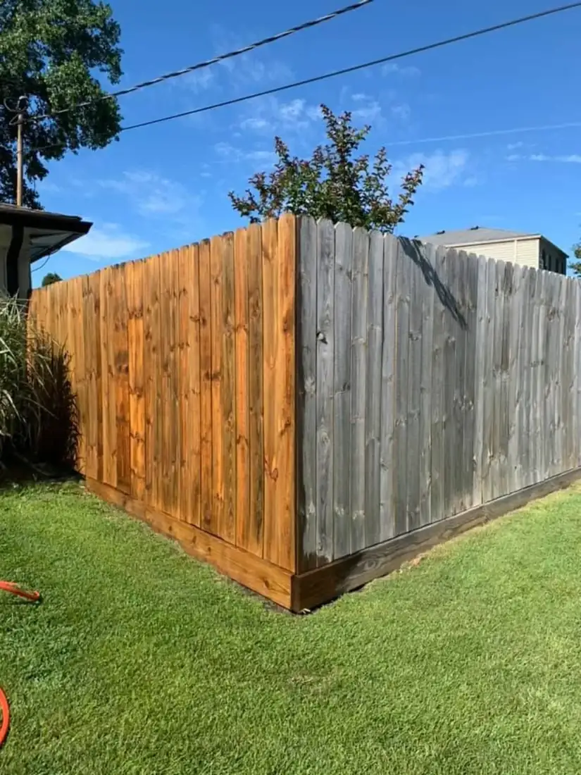 Wood privacy fence before and after cleaning, half weathered gray and half restored