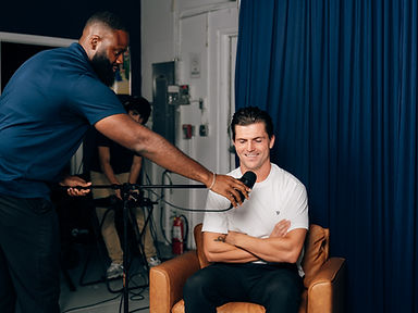A producer adjusting a studio microphone for Jordan Dunin before a recording