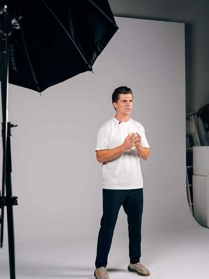 Full-body studio portrait of Jordan Dunin in a white t-shirt and black trousers