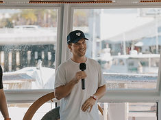 Jordan Dunin speaking with a handheld microphone in front of a room full of people