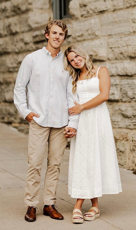 Sawyer and his wife Kylee standing together in front of a stone wall