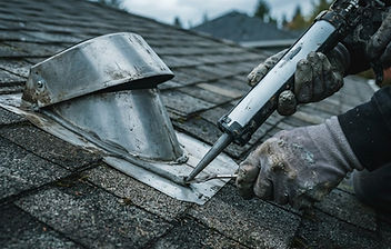 Close-up of a roofer sealing flashing and a vent boot