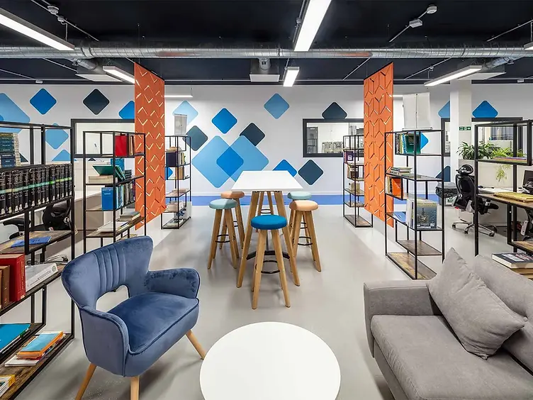 Contemporary open-plan office break-out area with a high table, colourful stools and soft seating