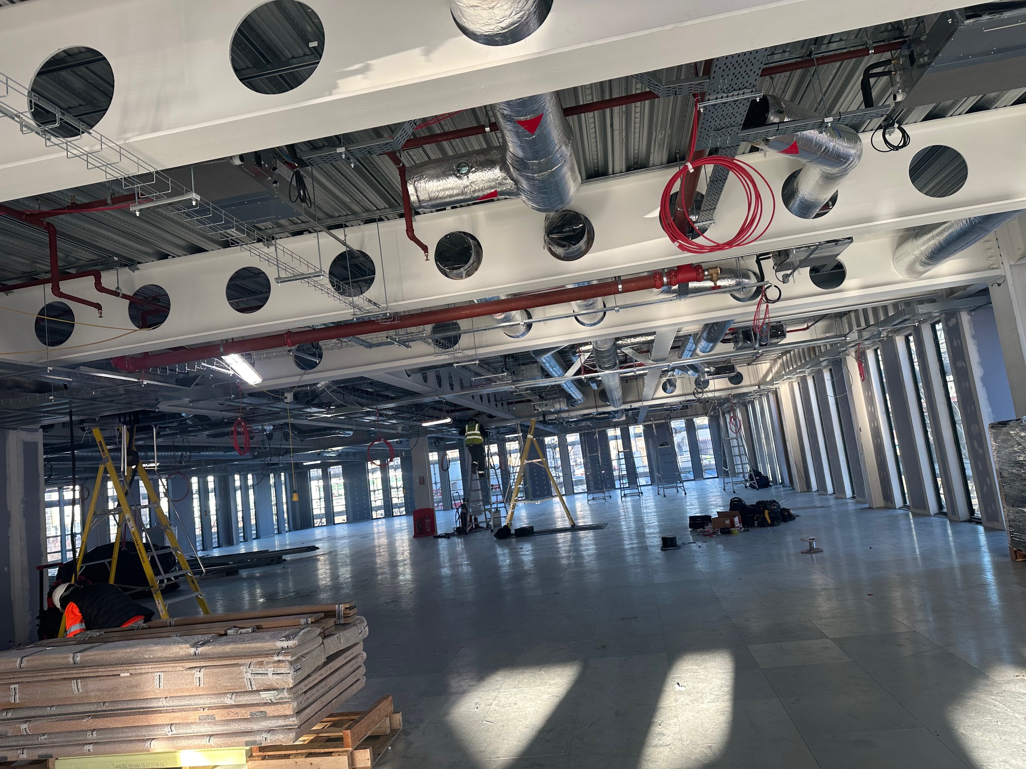 Open-plan commercial space under construction with structural and service infrastructure overhead